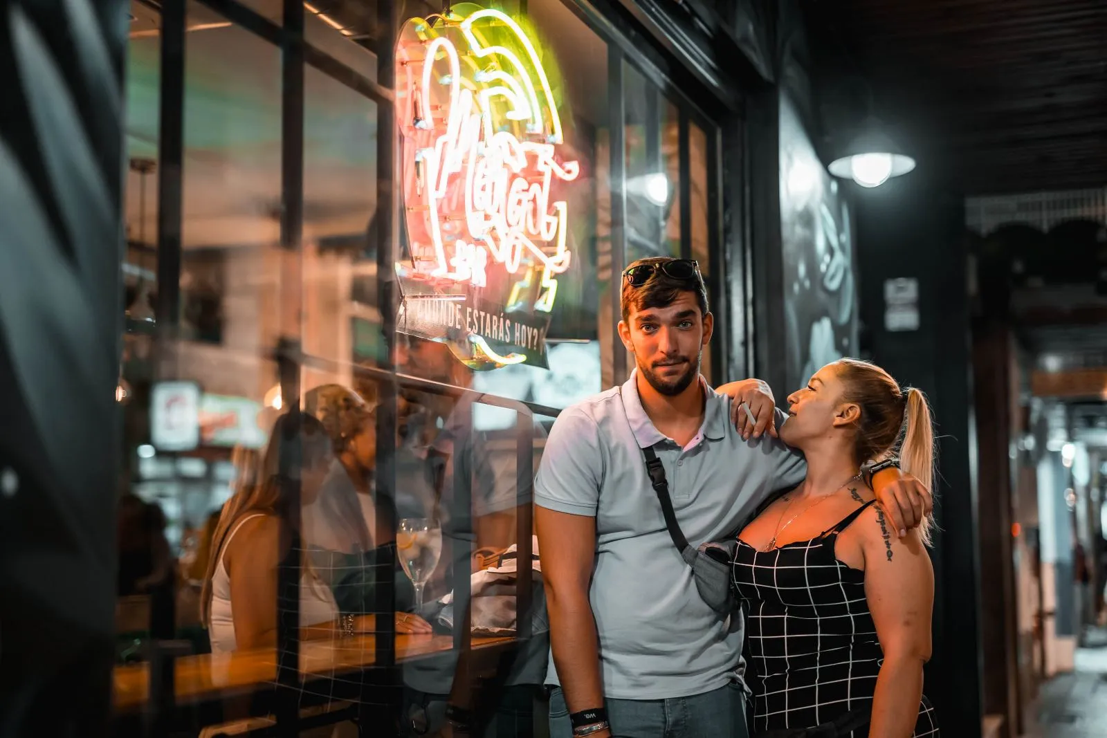Pareja junto a la fachada de neón de Margot Bar de noche